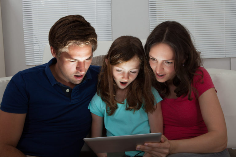 family of three surprised using tablet at home